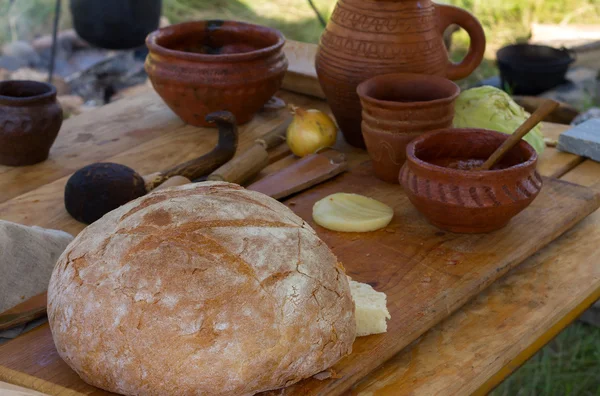 Antiguos platos de madera y arcilla con pan sobre una mesa — Foto de Stock