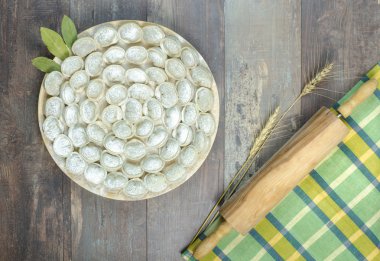 Meat dumplings russian pelmeni with rolling-pin on wooden background clipart