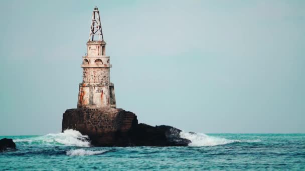 海浪冲击着旧的白色灯塔和深灰色的悬崖峭壁 拍打着浪花 在蓝云的天空中与世隔绝 慢动作保加利亚黑海沿岸的阿赫托波尔 — 图库视频影像