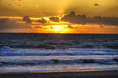 Atlantik 'e yansıyan altın rengi, sakin kumlar ve tarihi ufuk çizgisi ile Cadiz sahilinde büyüleyici bir gün batımı. Yüksek kalite fotoğraf