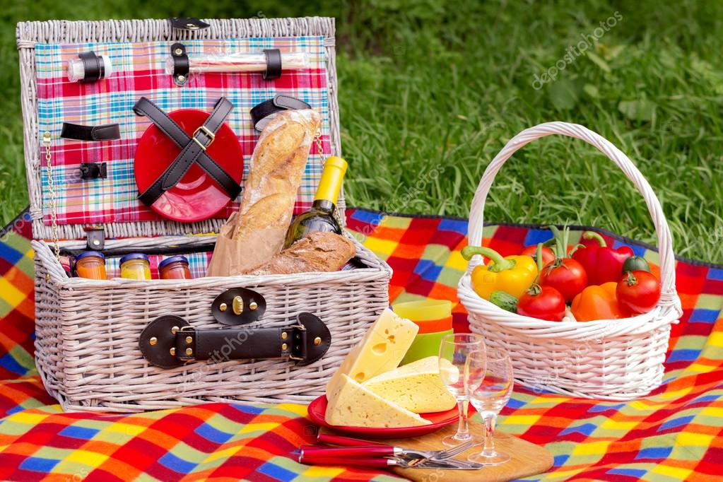 Picnic on the grass. Picnic basket with vegetables and bread. A — Stock