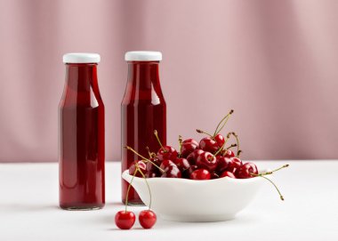 Kiraz bir kase ve iki şişe vişne suyu.