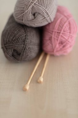 Ahşap örgü iğneleri ve örgü iplikleri. Pembe ve kahverengi. Seçici odak.