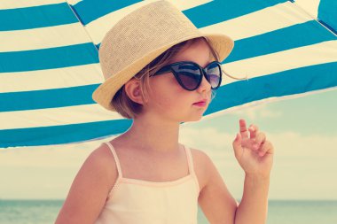 Little cute girl on the beach in big glasses.