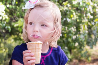 Pretty little girl eating ice cream in the summer the Park.
