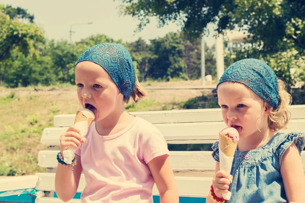 Little cute girls (sisters) eat ice cream. Selective focus.