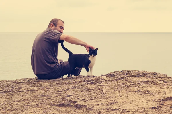 Adam ve sahilde oturan kedi.