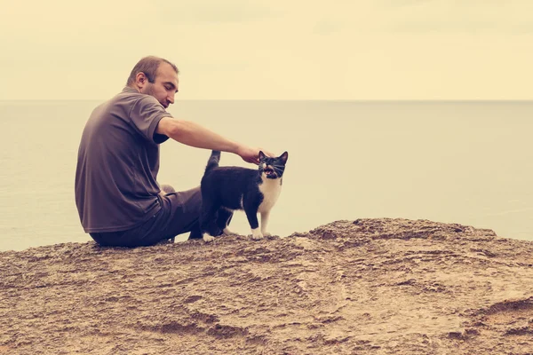 Adam ve sahilde oturan kedi.