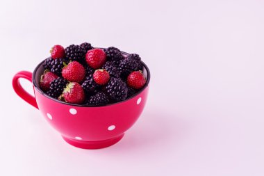 Böğürtlen ve çilek kırmızı bir tabak içinde. İzole adam