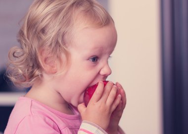 Komik kız (2 yıl) bir şeftali yemek.