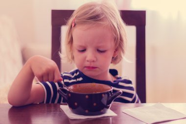 Küçük şirin kız çorba yiyor.