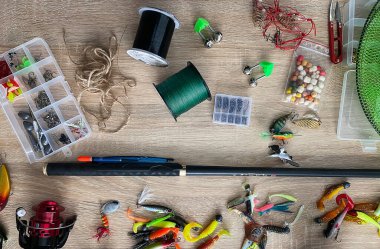 Tahta arka planda izole edilmiş olta, bobin ve balık yemi, üst manzara.