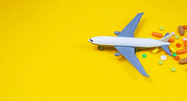 Model airplane with multicolored pills from motion sickness close-up on a yellow background. concept illness in travel.selective focus — Stock Photo, Image