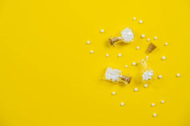 Sarı arka planda homeopatik cam şişe. Alternatif bitkiler ilaç homeopati