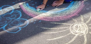 Sevimli küçük çocuk tebeşirle yazı dışarıda, tebeşirle çiziyor. Seçici odaklanma. Doğa