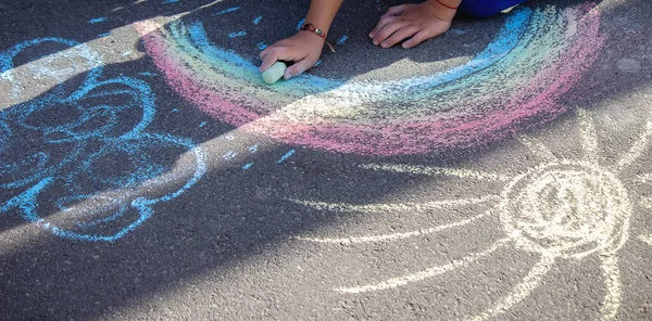 Sevimli küçük çocuk tebeşirle yazı dışarıda, tebeşirle çiziyor. Seçici odaklanma. Doğa