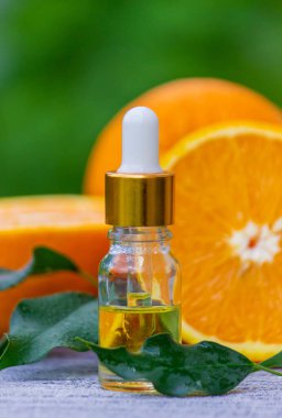 Şişe içinde portakal yağı, arka planda taze meyve parçaları. Doğal tatlar. Seçici odak
