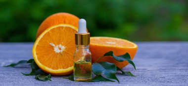 Şişe içinde portakal yağı, arka planda taze meyve parçaları. Doğal tatlar. Seçici odak