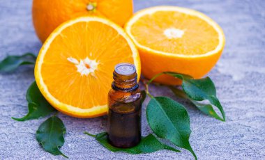 Şişe içinde portakal yağı, arka planda taze meyve parçaları. Doğal tatlar. Seçici odak