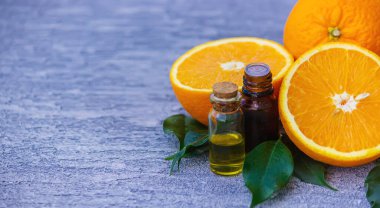 Şişe içinde portakal yağı, arka planda taze meyve parçaları. Doğal tatlar. Seçici odak