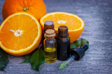 Şişe içinde portakal yağı, arka planda taze meyve parçaları. Doğal tatlar. Seçici odak