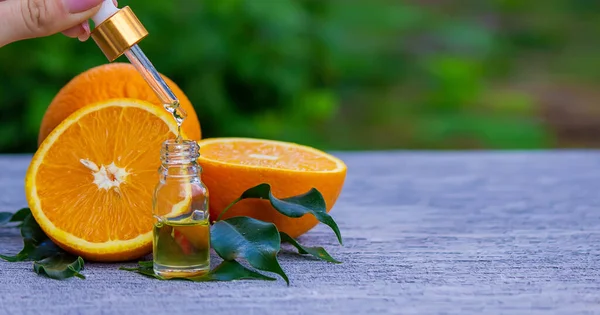 Şişe içinde portakal yağı, arka planda taze meyve parçaları. Doğal tatlar. Seçici odak