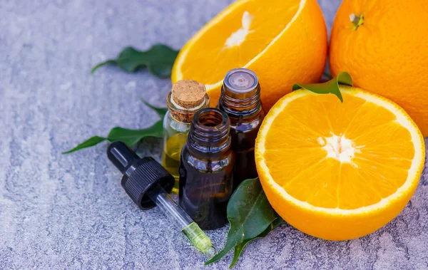 Şişe içinde portakal yağı, arka planda taze meyve parçaları. Doğal tatlar. Seçici odak