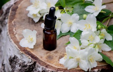Essential oil and jasmine flowers on a wooden background. Cosmetic procedures. Selective focus