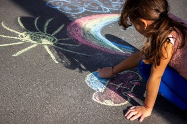 Kız gökkuşağı, güneş ve asfalta tebeşir çiziyor. Seçici odak