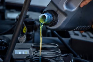 Bir araba tamircisi araba motoruna yağ döker. Seçici odak