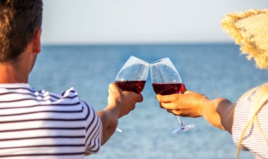 Deniz kenarında şarap içen romantik bir çift.