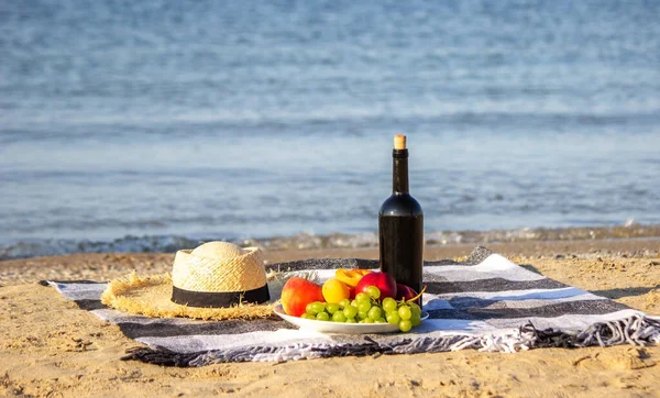Picnic blanket, wine, fruit, beautiful sea beach. Selective focus — Zdjęcie stockowe