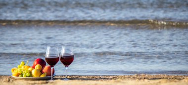 Piknik battaniyesi, şarap, meyve, güzel deniz plajı Seçici odak