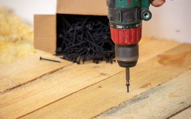 Adam vidaları tahtaya çeviriyor. Evdeki zeminin tamiri. Seçici odaklanma. İnter