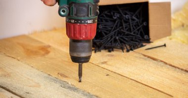 Adam vidaları tahtaya çeviriyor. Evdeki zeminin tamiri. Seçici odaklanma. İnter