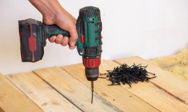 Adam evde tamirat yapıyor, tornavida, vida, testere. Ahşap zemin. Seçici odak