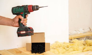 Adam evde tamirat yapıyor, tornavida, vida, testere. Ahşap zemin. Seçici odak