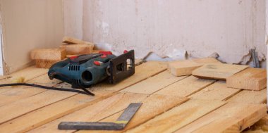 Bir adam elektrikli testereyle tahtayı keser. Evdeki zeminin tamiri. Seçici odak.