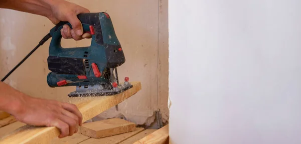 Un hombre corta una tabla con una sierra eléctrica. Reparación del piso de la casa. Enfoque selectivo. —  Fotos de Stock