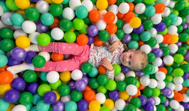 Mutlu Kız Renkli Top havuzunda Oynuyor ve Yalan Söylüyor.