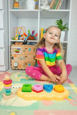Küçük bir kız, iyi motor becerileri geliştirmek için tahta bir oyuncakla oynuyor.