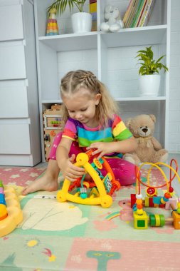 Kız çocuk odasında interaktif ve ahşap oyuncaklarla oynuyor..