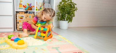 Kız çocuk odasında interaktif ve ahşap oyuncaklarla oynuyor..