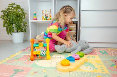 Küçük mutlu kız çocuk odasında oyuncaklarla oynuyor.