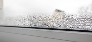 Soğuk havada yoğun yoğunlaşma ve su damlaları sisli plastik bir pencere camına yakın plan..