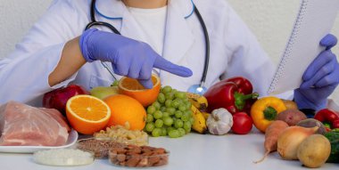 Hasta muayenesi sırasında portakalın faydalarını açıklayan beslenme uzmanı.