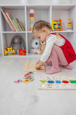 Küçük kız tahtadan bir eğitim numarası bulmaca oyuncağıyla oynuyor..