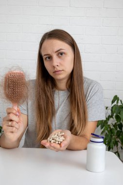 Saç fırçası ve kel kalmak için bir şişe vitamin tutan bir kadın..
