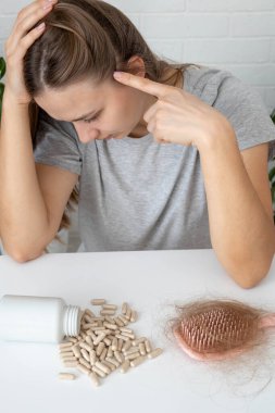 Kafasını tutan kadın, saçlarını ayırıyor ve incelme ya da saç dökülme sorunu yaşıyor..