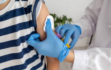 Doktor hastanın koluna, aşısına ve hastalığın önlenmesine aşı yapıyor..